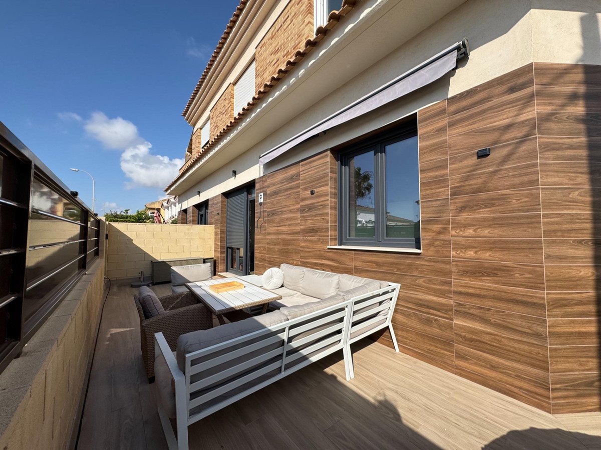 Modern terrace with comfortable outdoor sofa, chairs, and dining table. Features wood-like tiling and a retractable awning.