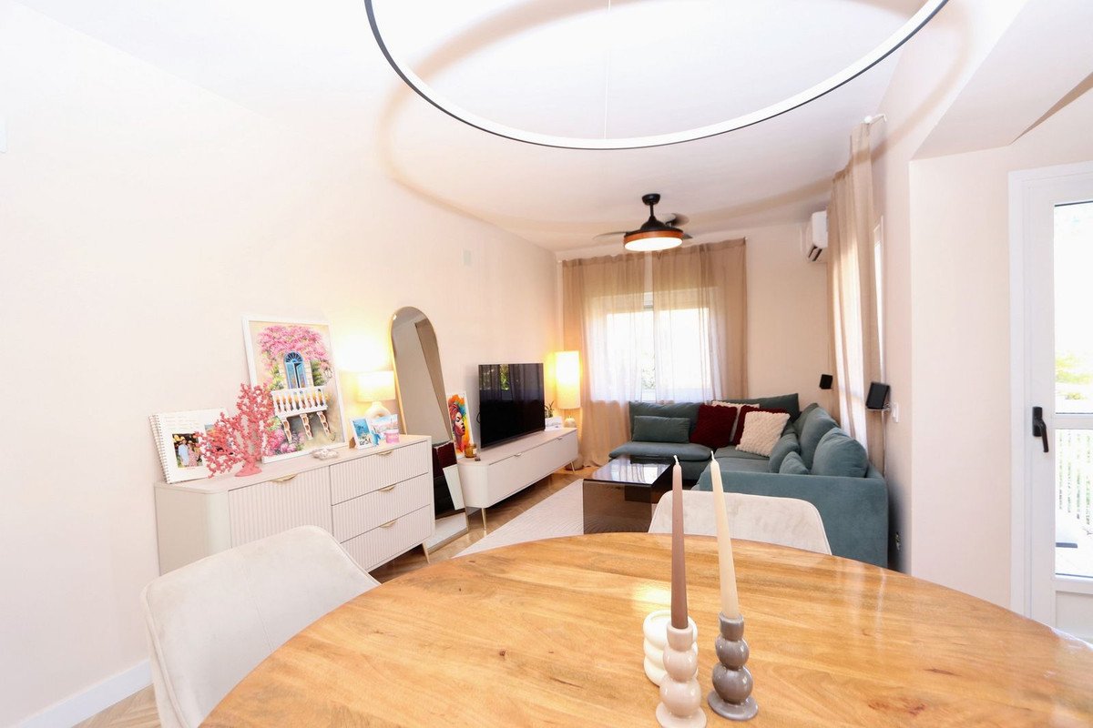 A modern living room with a teal sectional sofa, coffee table, TV stand, and a round wooden dining table with candles.