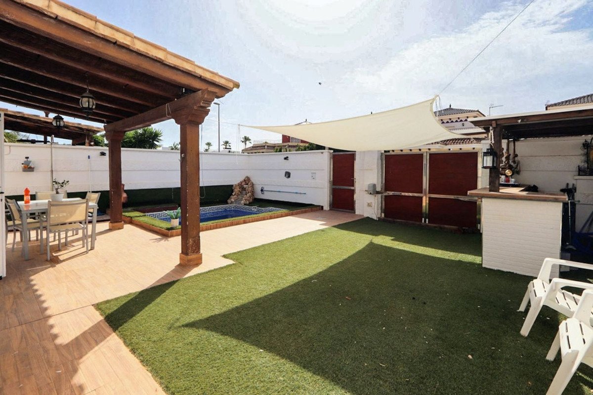 Covered outdoor lounge area with swimming pool and artificial grass