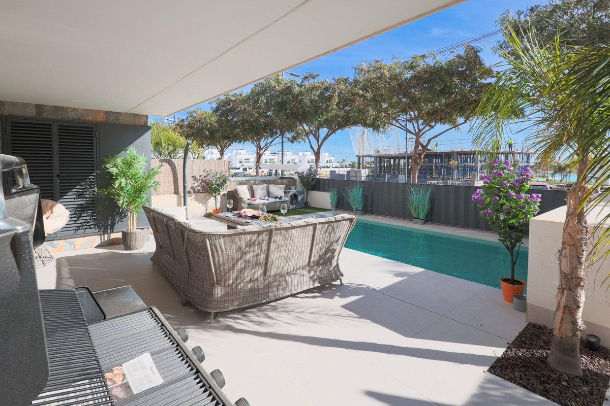 Outdoor patio with a pool, lounge seating, dining table, and grill under a covered area.