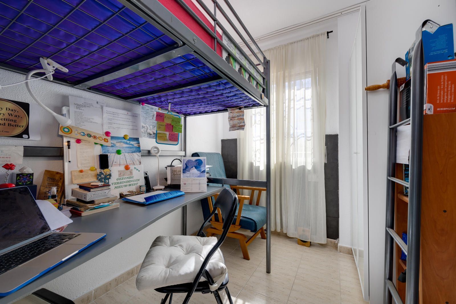 Kleine slaapkamer met hoogslaper, bureau en stoel.