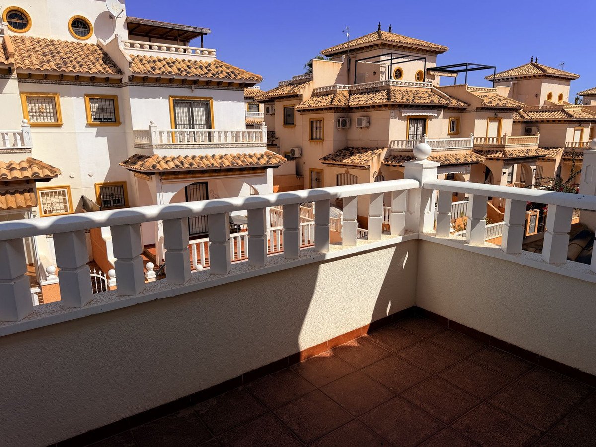 Terrace view of Mediterranean-style apartments with white railings under a clear blue sky.