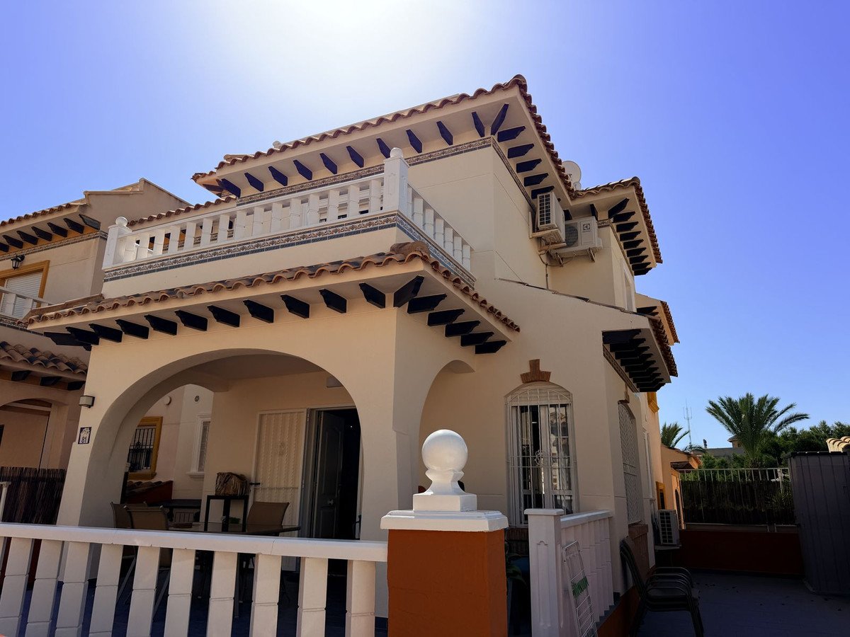 Exterior view of a house with a balcony, archway leading to a terrace, and visible air conditioning units.