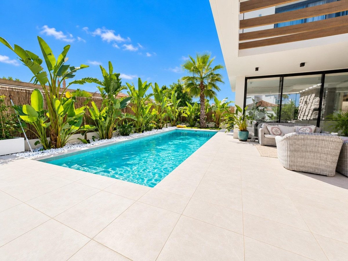 A luxurious modern villa features a private swimming pool and outdoor lounge area with tropical greenery and palm trees.