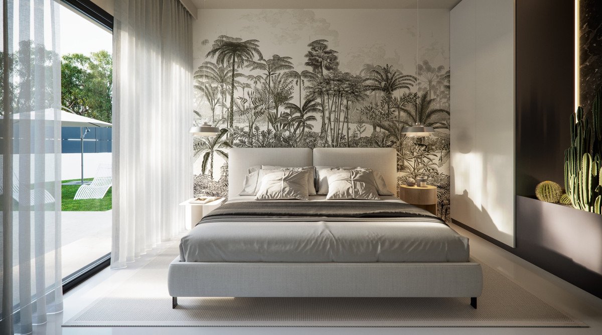 Bedroom with king-size bed, jungle-themed wallpaper, and large windows overlooking a garden with loungers and umbrella.