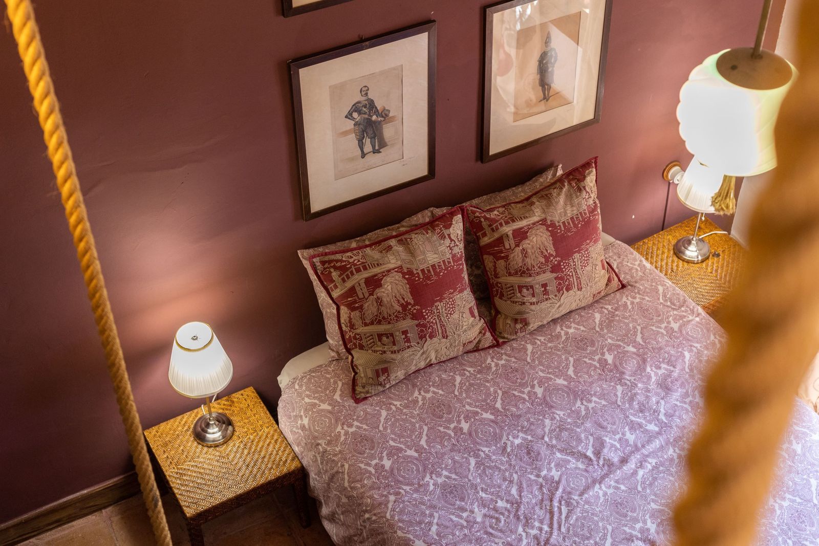 Slaapkamer met rode muren, bed en kunstwerken