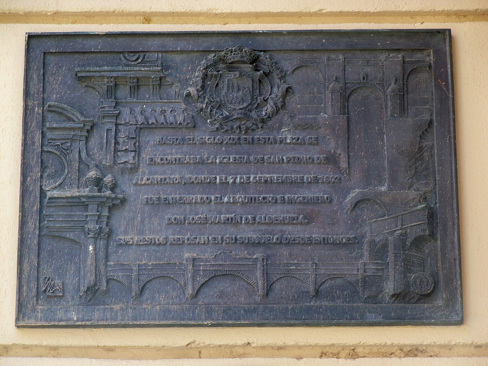 Alt text: A bronze plaque with an emblem and text, mounted on a wall.