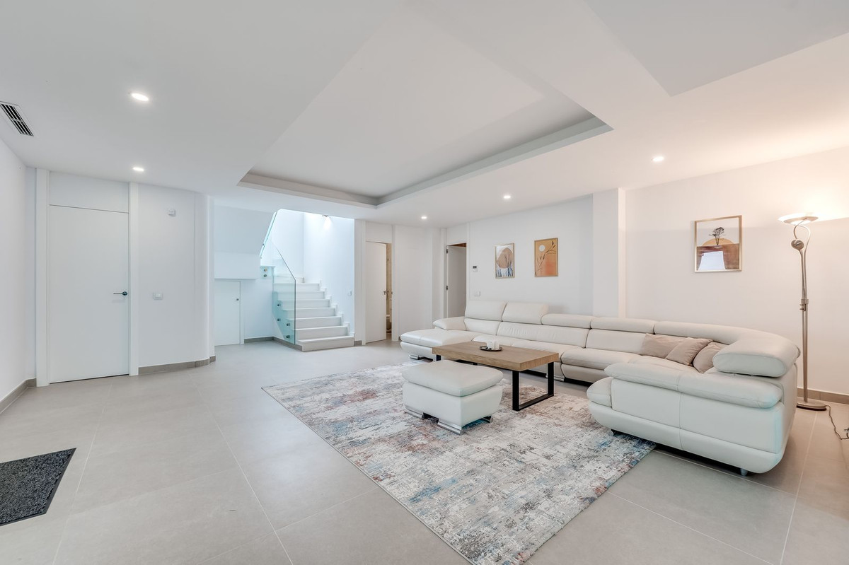 Moderne woonkamer met witte trap en lichte inrichting