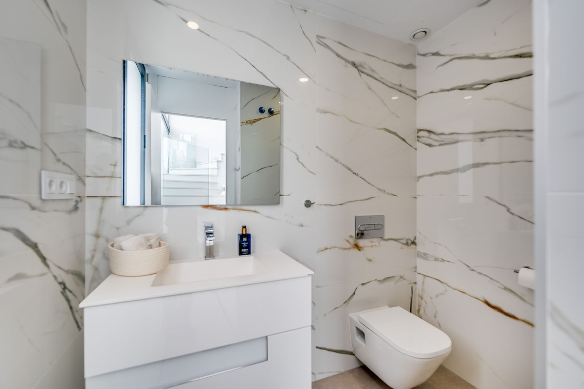 Moderne badkamer met marmeren wand en wit sanitair.