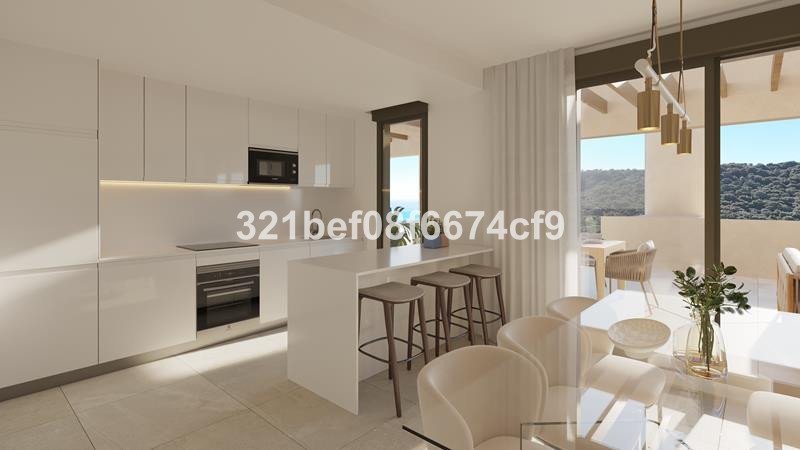 Modern kitchen with island and stools, opening onto a balcony with a view of hills and the sea.