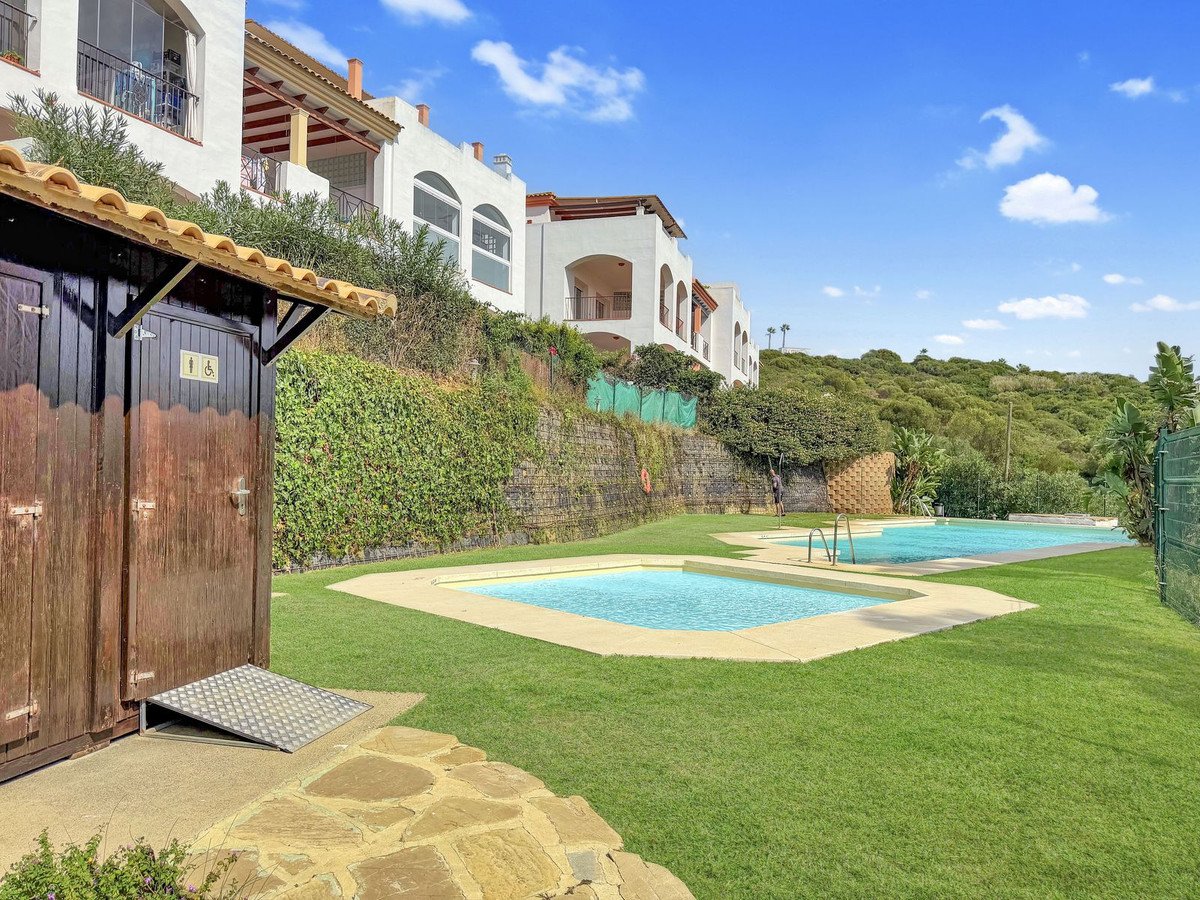 Outdoor pool area with grass, two pools, and resort villas in background