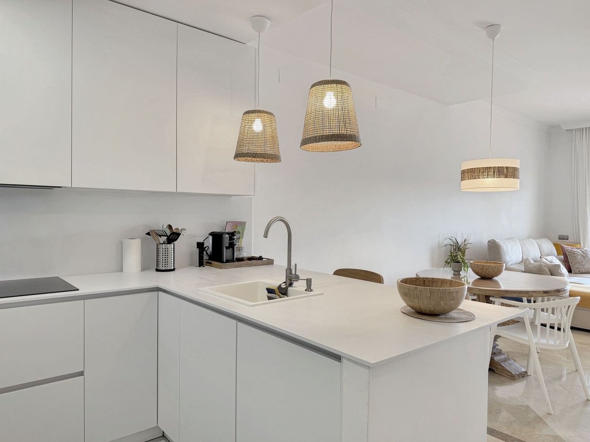 Modern open-plan kitchen and living room with white cabinets and pendant lights
