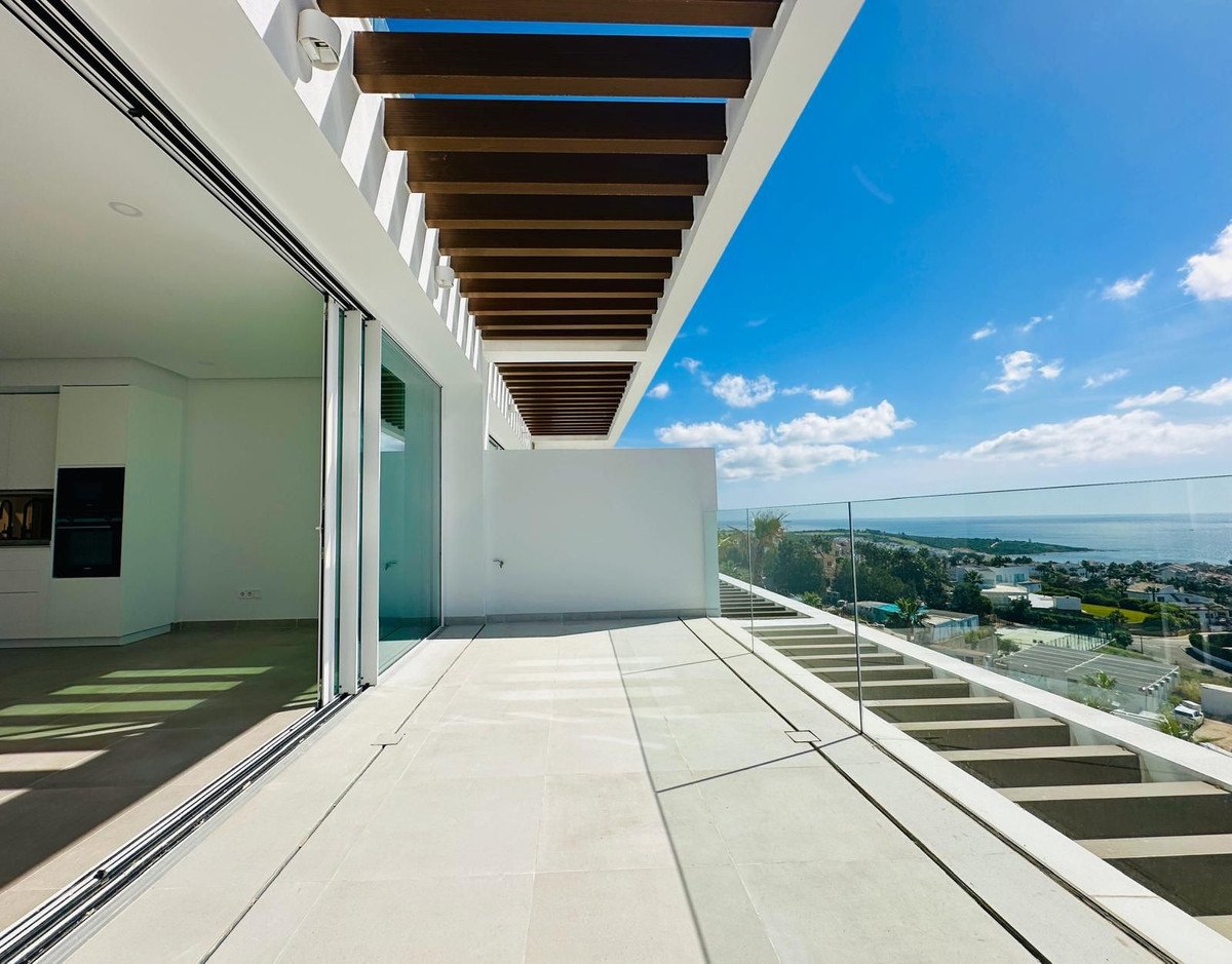 Spacious terrace with a modern kitchen view and a stunning sea view under a blue sky.