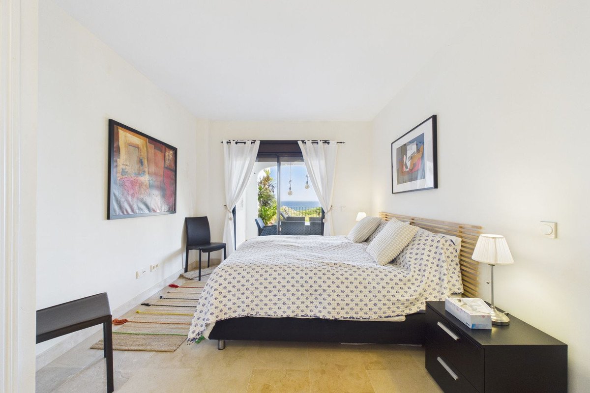 A spacious bedroom with a king-size bed, large window offering a sea view, and access to a balcony with outdoor seating.