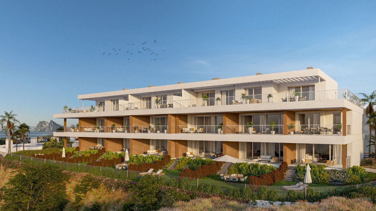 Modern apartment building with multiple balconies and terraces offering sea and mountain views.