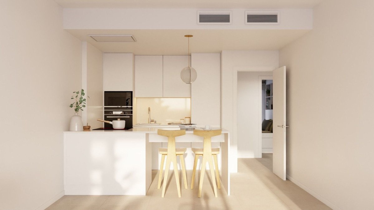 Modern white kitchen with an island, bar stools, and built-in appliances. Natural light fills the space.