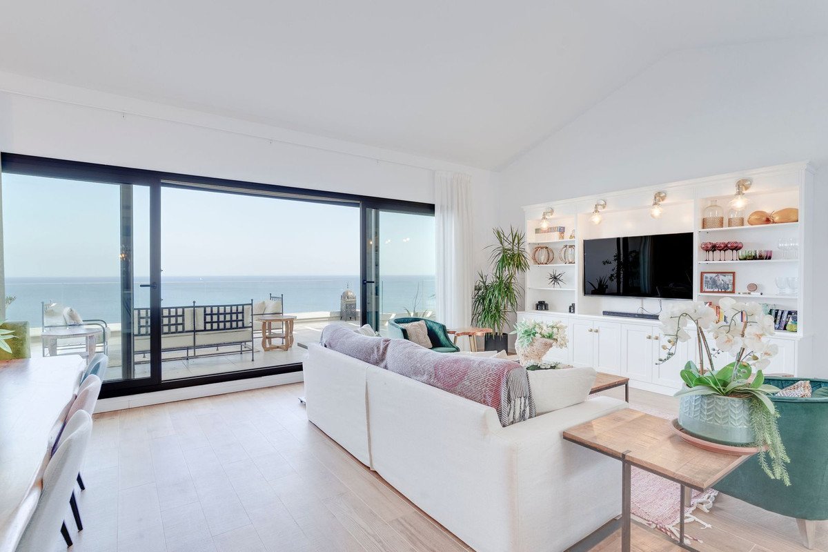 Bright living room with a large window showing an ocean view, balcony, and built-in entertainment center.