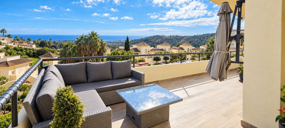 A terrace with outdoor furniture, overlooking a sea view and nearby buildings.