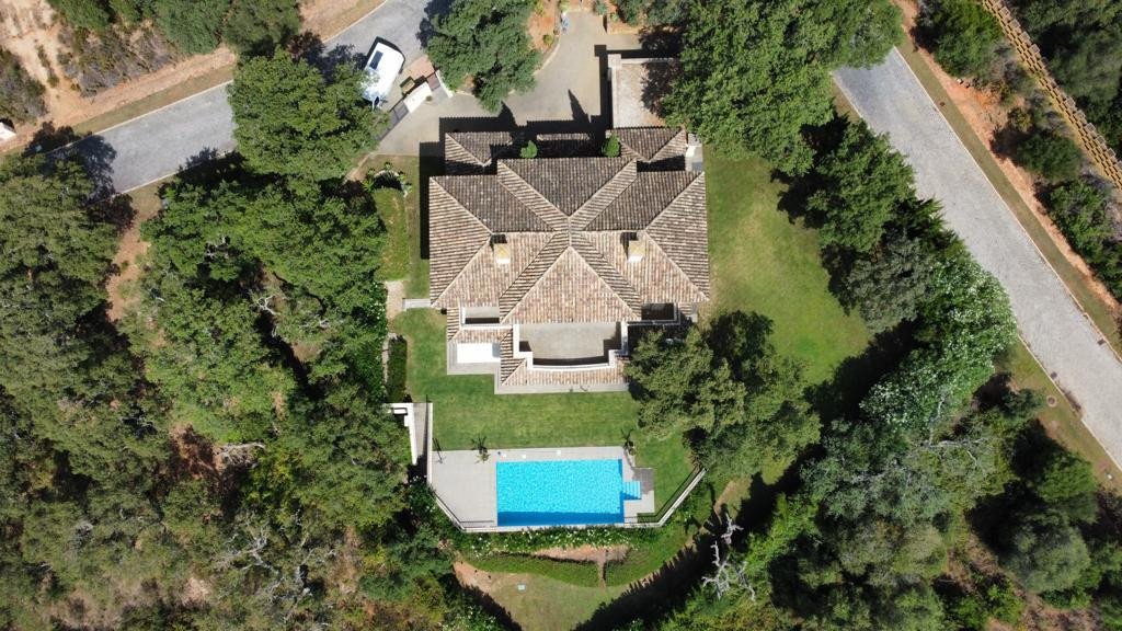 Aerial view of a villa with a swimming pool and surrounding trees.