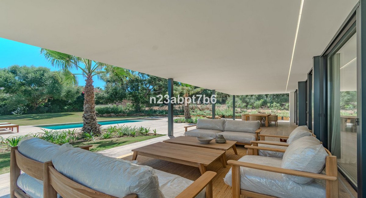 Covered patio with comfortable seating, coffee tables, and a view of a swimming pool and garden.