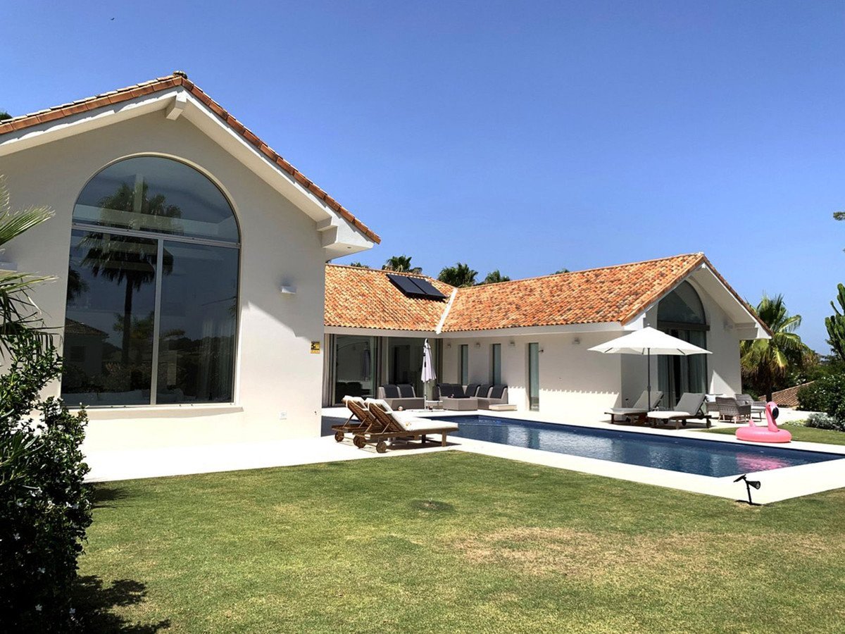 Modern villa with a swimming pool, sunbeds, and a flamingo inflatable on a sunny day.