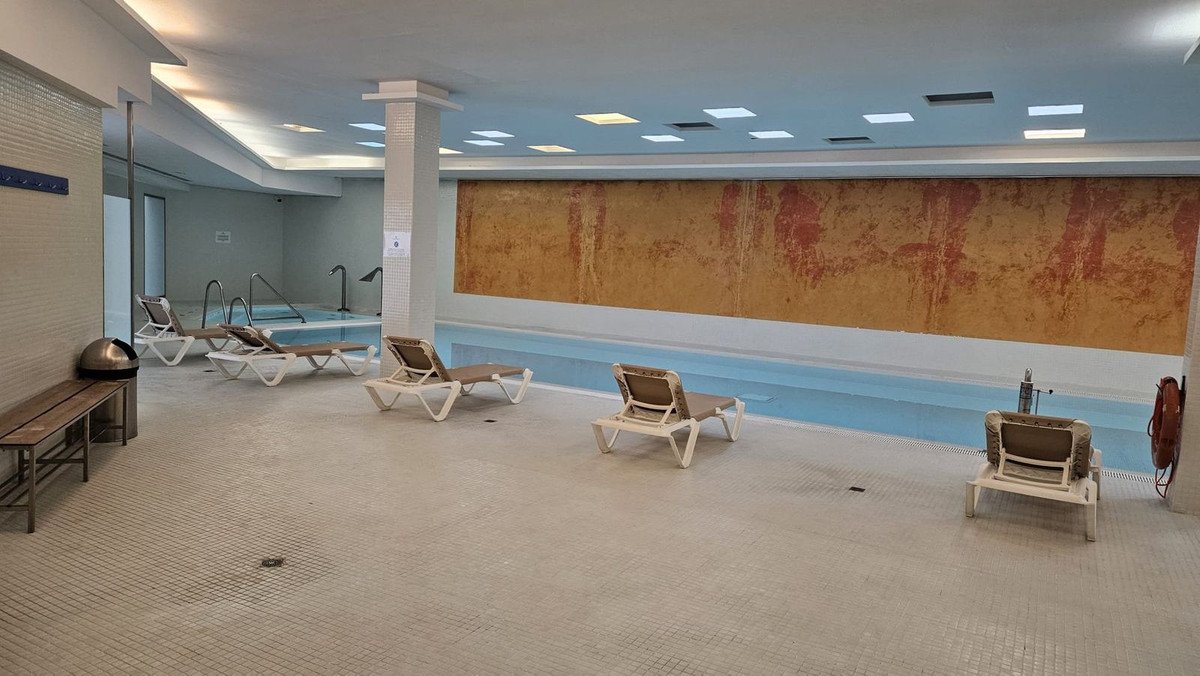 Indoor swimming pool with lounge chairs and a decorative wall