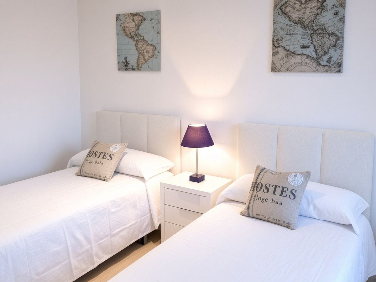 A bright twin bedroom with white beds, decorative map art on the wall, and a bedside lamp.