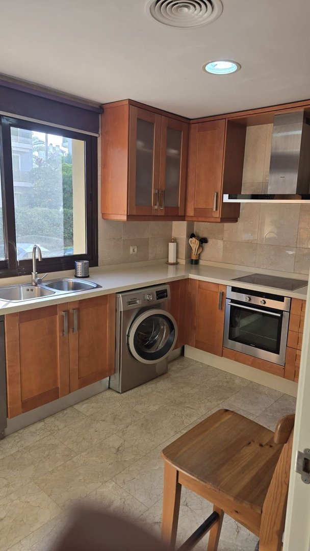 Modern kitchen with wooden cabinets, stainless steel appliances, and a window view