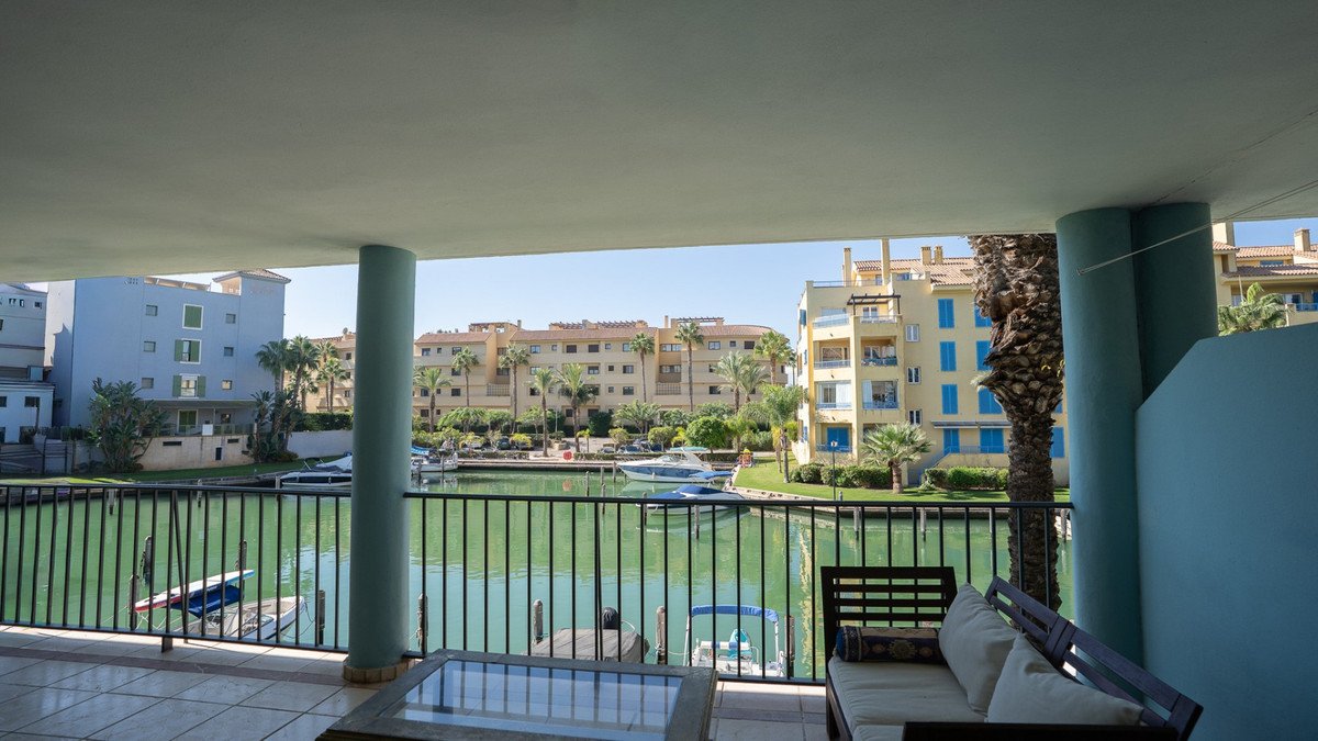 View from a terrace overlooking a canal with boats and apartment buildings.