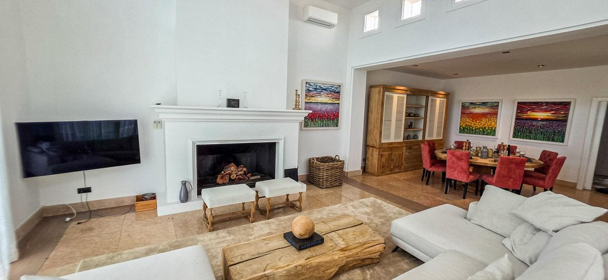 Spacious living and dining area with a fireplace, TV, and large dining table with red chairs.