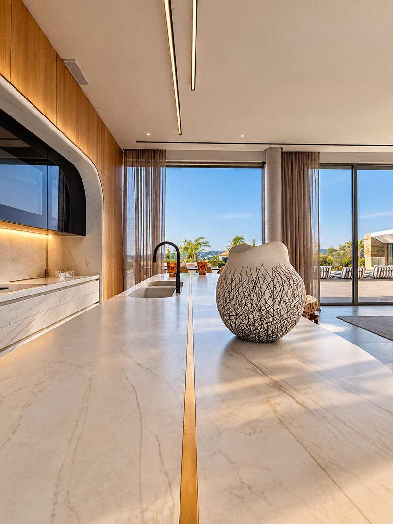 Modern kitchen island with marble countertop, featuring a sink and a large decorative vase with a stunning sea view.