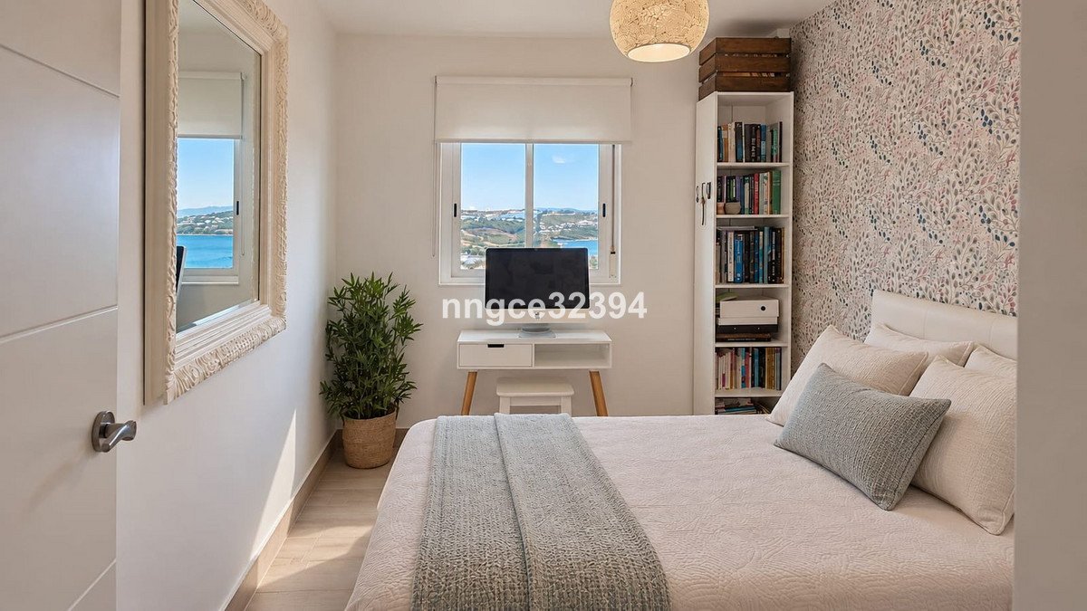 Bedroom with a bed, desk, and a scenic sea view visible through the window.