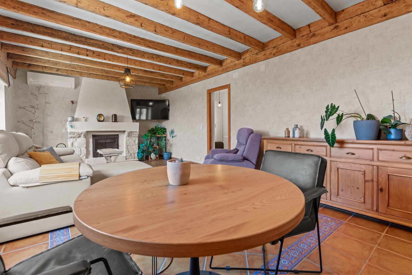 Gezellige woonkamer met open haard en houten balken plafond.