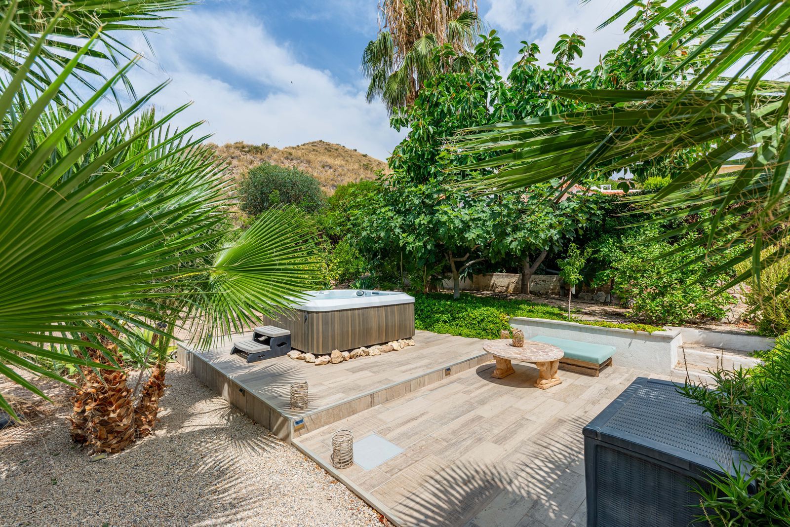 Jacuzzi in een weelderige tuin met groene planten en een zonnige sfeer.