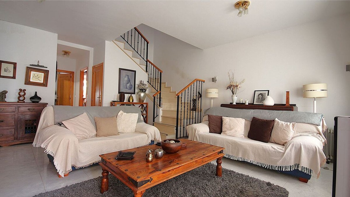 Spacious living room with two sofas, a wooden coffee table, and stairs leading to the upper floor.