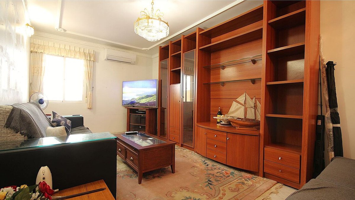 Interior of a living room with a large wooden built-in shelving unit, a television, a sofa, and a coffee table.