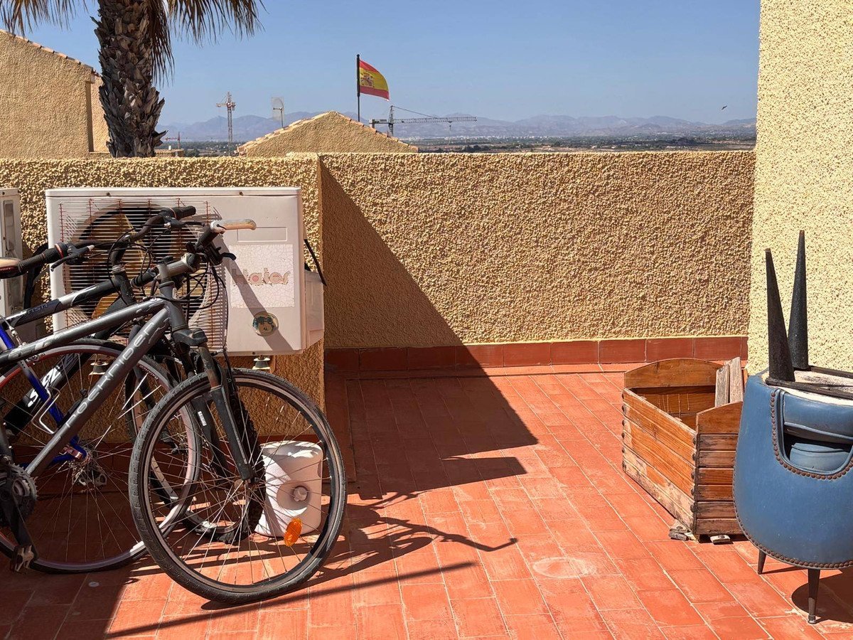 Rooftop terrace with bicycles, air conditioner, and distant mountain view.