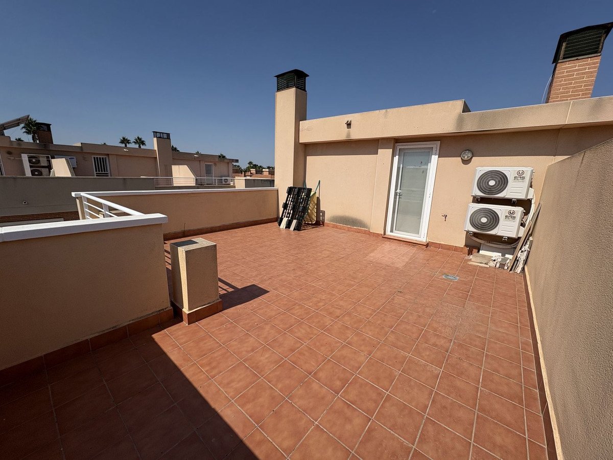 Spacious rooftop terrace with terracotta tiles, featuring air conditioning units and a glass door with access to the building.