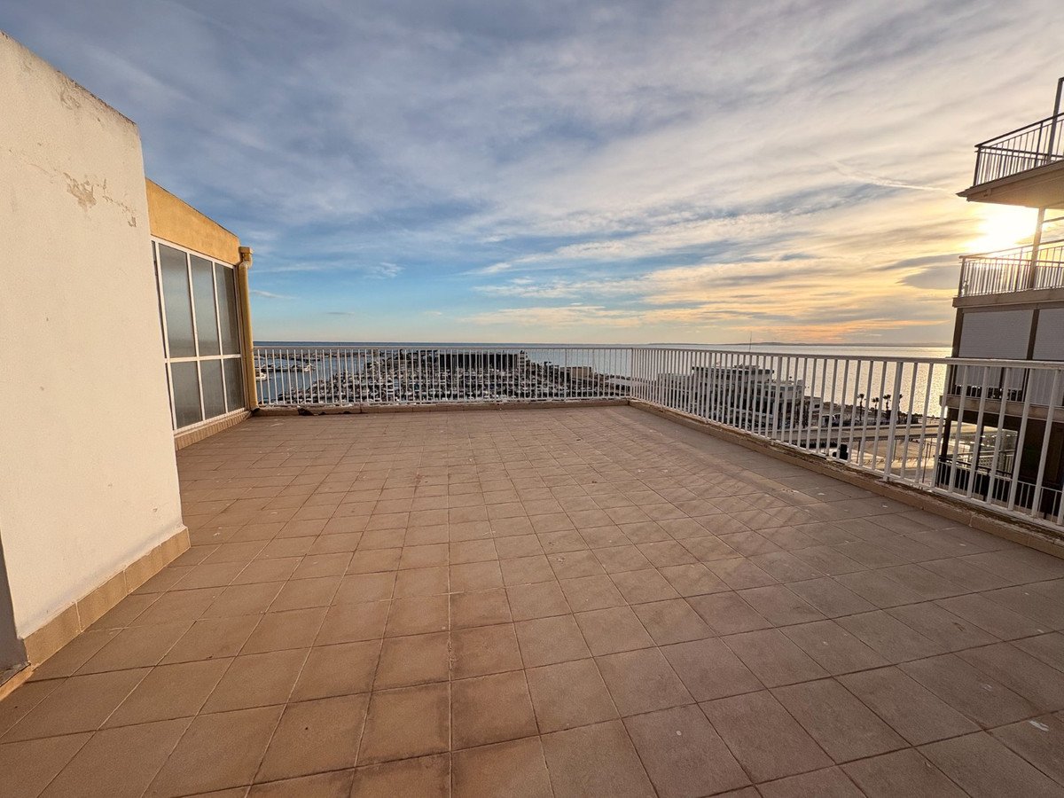 Large tiled balcony with ocean view and marina at sunset.