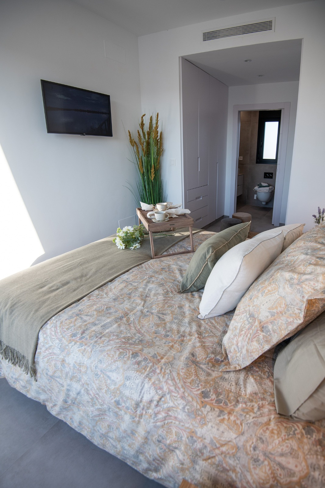 Slaapkamer met ensuite badkamer en neutrale decoratie.