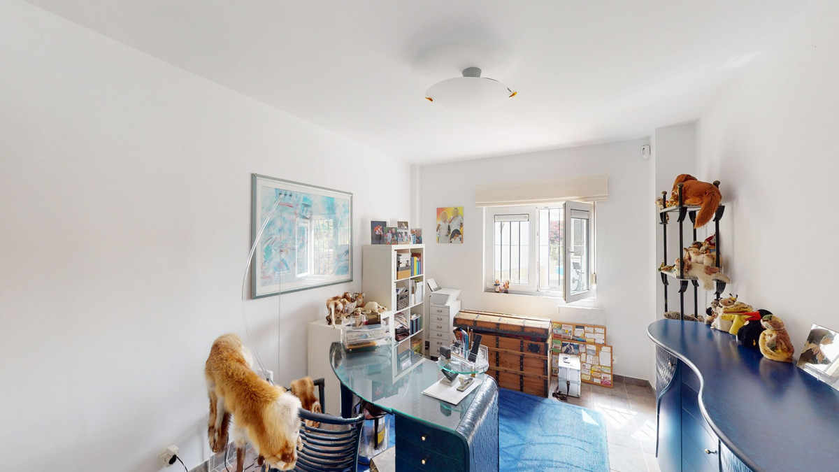 Lichte werkkamer met glazen bureau en blauw accenten.