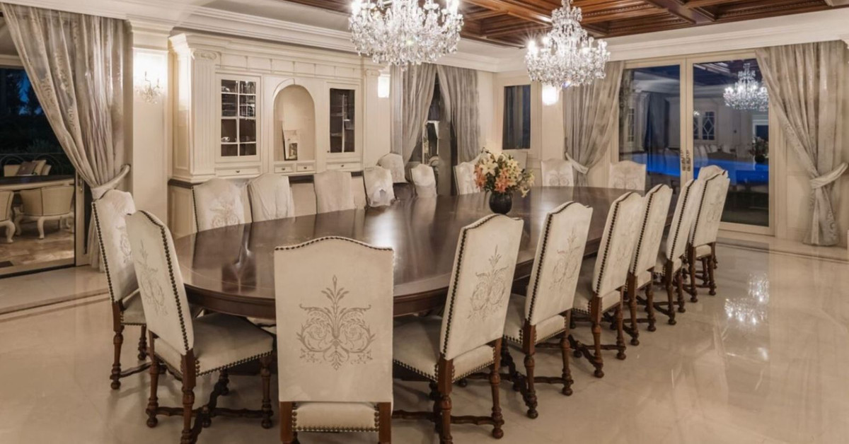 Luxe eetkamer met kroonluchter en lange tafel.