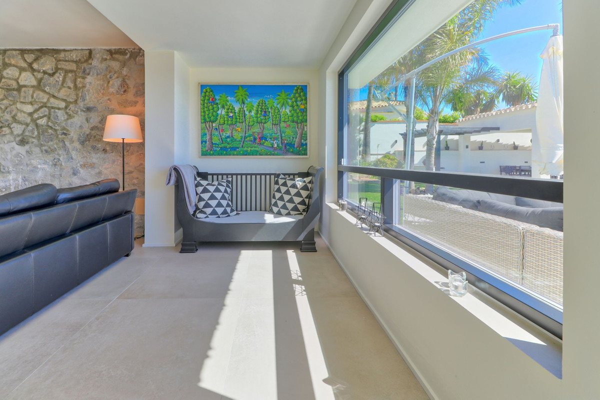 Stijlvol villa interieur met bank, kunst en uitzicht op de tuin.