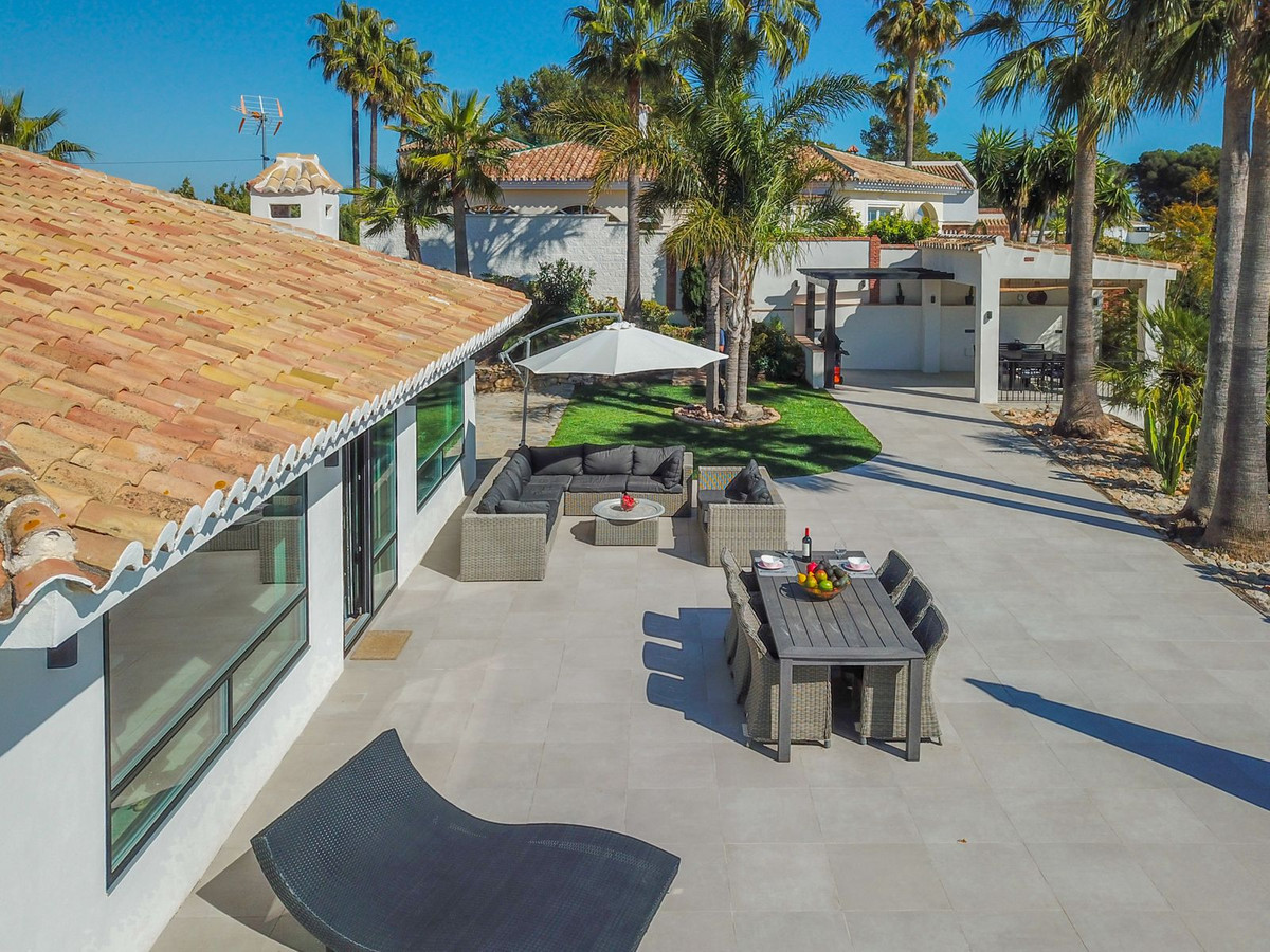 Buitenterras van villa met eethoek, lounge en ligbed