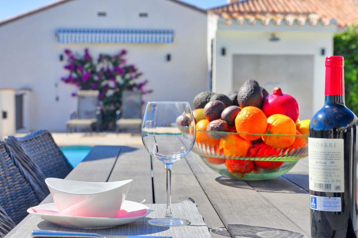 Buiteneettafel met fruit, wijnglas en wijnfles.
