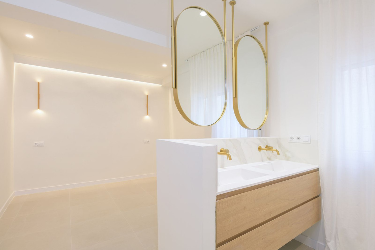 Moderne badkamer met wastafelmeubel en gouden spiegels.