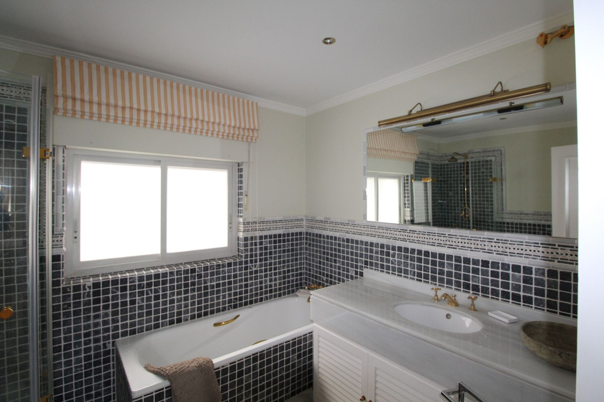 Badkamer met ligbad, tegels en raam