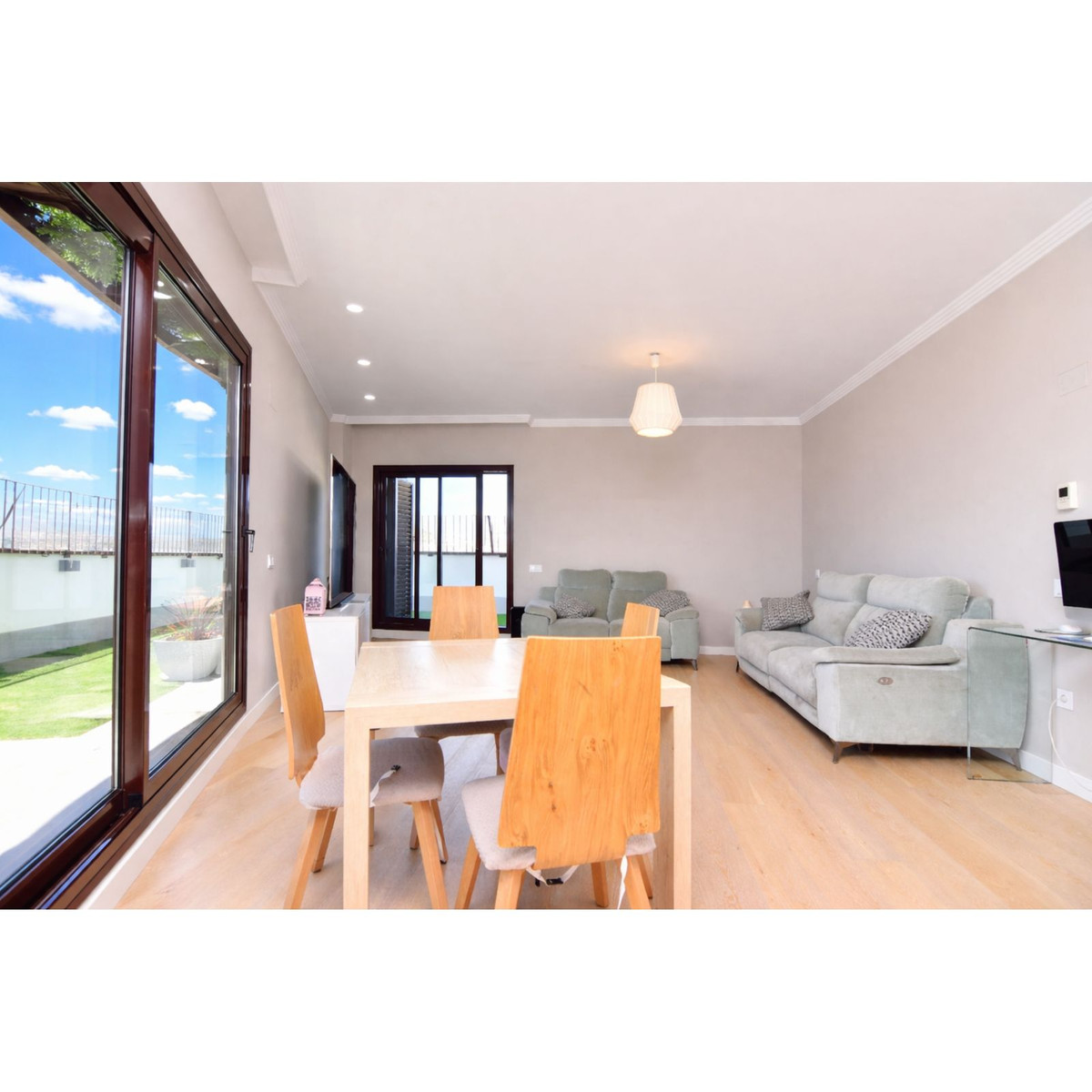 Lichte en luchtige woon- en eetkamer met houten meubels en grote ramen.