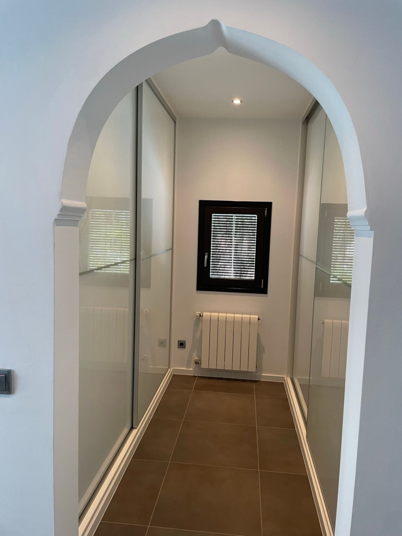 Kleine hal met boogvormige ingang en inbouwkasten.