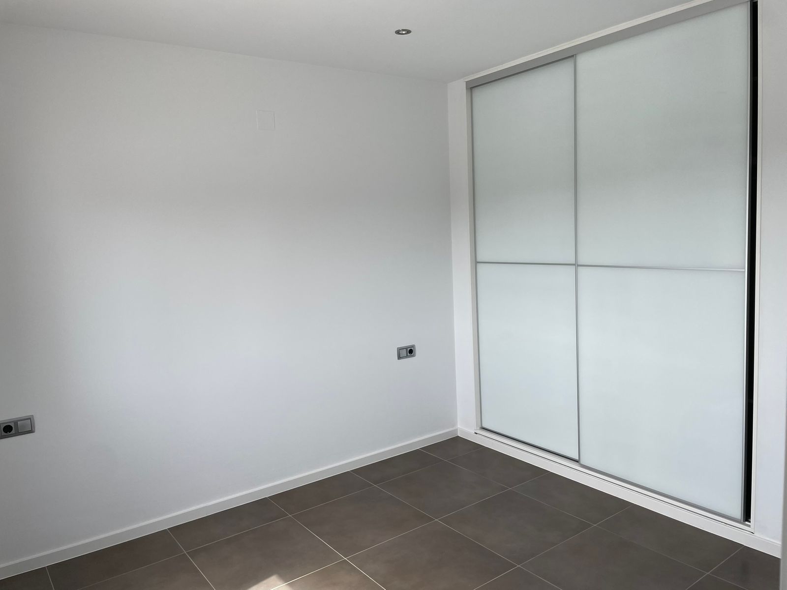 Moderne slaapkamer met witte muren en schuifwandkast.